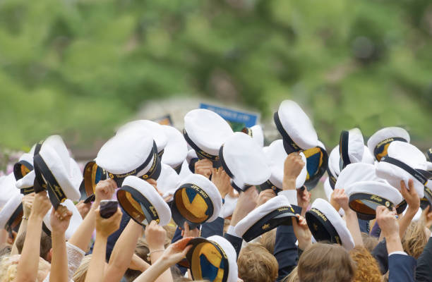 STOCKHOLM, SWEDEN - JUN 13, 2017: Hands holding many swedish white graduation caps, green trees in the background at the dance school Balettakademien, June 13 2017,Stockholm,Sweden